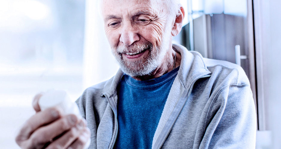 Elderly man reading prescription bottle